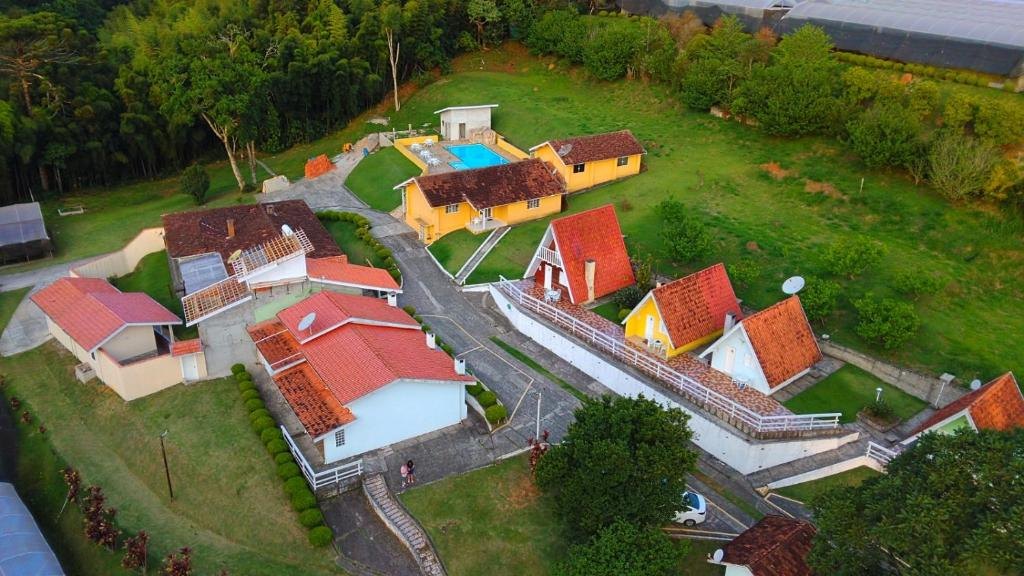 Vista aérea dos chalés no alto do terreno e da piscina