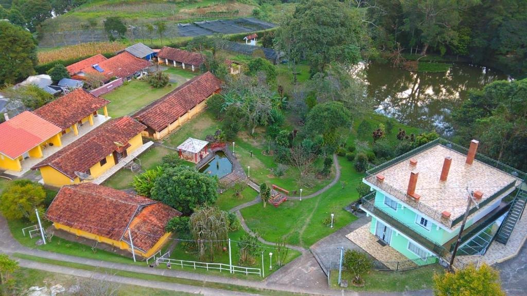 Vista aérea da pousada com jardim, lago e as casas de telhado cerâmico